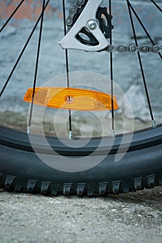 Close-up of a plastic orange reflector on the spokes of a bicycle wheel