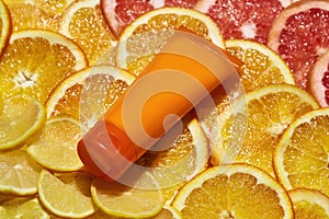 Close up of plastic orange tube with natural vitamin C skin care product isolated over fresh juicy orange citrus fruit