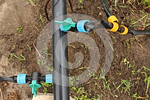 Close-up - a plastic pipeline and drip tapes connected to it with fittings, taps