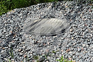 A close-up of a plastic septic tank manhole cover, manhole lid that covers a sewage tank with gravel rocks around