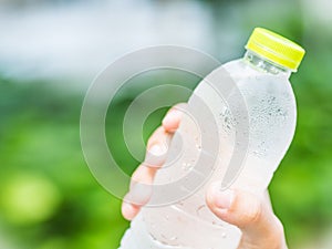 Close-up plastic water bottle in woman hand after jogging in garden backgroound