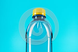 Close-up of plastic water bottle with yellow cap on the blue background