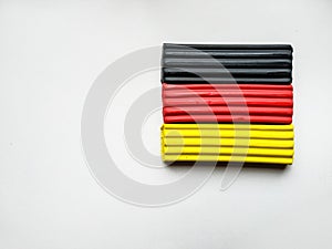 Close-up plasticine of different colors lies on a white background with copy space. Black, red, yellow plasticine like a german