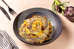 Close up of a plate with artichokes pasta, fettuccine and bacon