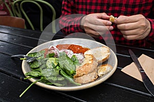 Close up of a plate of Australian style breakfast or brunch with fresh raw spinach leaves, bread, and meatballs.