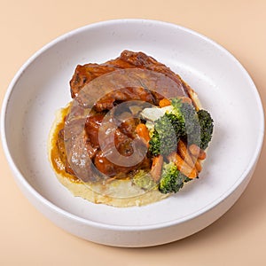 Close-up plate of beef ribs in barbecue sauce with vegetables and mashed potatoes angle view