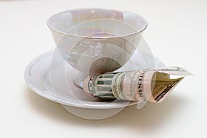 Close-up of plate with cup and bill tip on white table