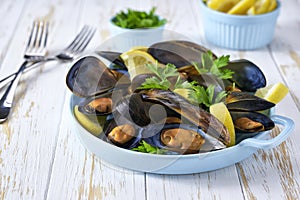 Close up of a plate with freshly cooked mussels on white table, selective focus