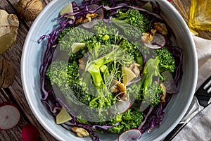 Close-up of plate with a healthy vegetarian salad of steamed broccoli, fresh radishes, walnuts, red cabbage, ginger and extra