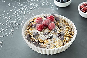 Close up of a plate with muesli, raisins, raspberries and coconut shreds