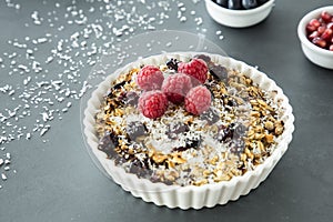 Close up of a plate with muesli, raisins, raspberries and coconut shreds photo