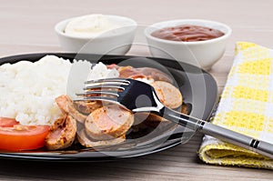 Close up of plate with rice, sausage, tomatoes, ketchup, mayonnaise