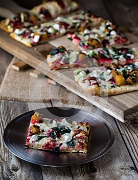 A close up of a plate with a slice of flat bread pizza and more in behind.