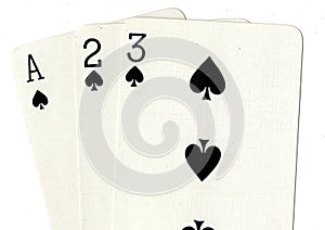A close up of playing cards showing an ace, two and three of spades.
