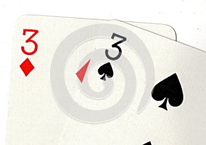 Close up of playing cards showing a pair of threes.