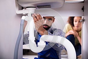 Close-up Of A Plumber Fixing Sink Pipe