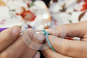 close-up point of view of a woman's fingers crocheting with the number 3 needle and green yarn photo