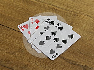 Poker cards on a wooden backround, set of nines of clubs, diamonds, spades, and hearts photo