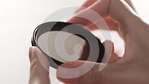 Close-up polarizing light filter in hands. Concept. Woman turns small lens on camera in hands. Setting gradient filter