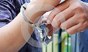 Close up police staff`s hands unlocking handcuffs on male accused hand by key