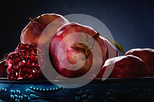 Close-up of pomegranate fruit and its parts in a blue plate of oriental style