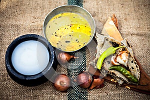 Close up of poor man`s complete milk on gunny bag`s background with white lentil,pearl millet roti or chapati and buttermilk or