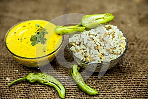 Close up of popular Indian & Asian lunch dish on brown colored surface i.e. Kadhi or Karhi  and kichdi or chawal with fresh green