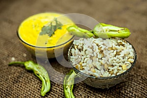 Close up of popular Indian & Asian lunch dish on brown colored surface i.e. Kadhi or Karhi  and kichdi or chawal with fresh green