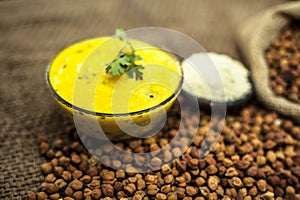 Close up of popular Indian & Asian lunch dish on brown colored surface i.e. Kadhi or Karhi  and kichdi with raw cickpeas and besan