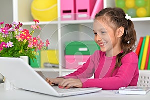 Porait of cute girl using laptop at desk photo