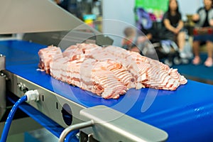 Close up pork or meat sliced on conveyor of automatic and precision slicer machine for industrial food manufacture