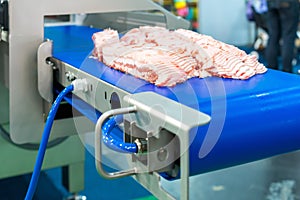 Close up pork or meat sliced on conveyor of automatic and precision slicer machine for industrial food manufacture