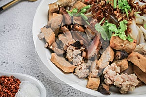 Close up pork,tofu,mushroom and coriander in Chinese Steamed Rice Noodles with sweet soy sauce in white plate.