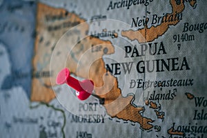 Close up of Port Moresby pin pointed on the world map with a pink pushpin