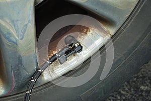 Close up of a portable air compressor connected to the valve stem of a car tire