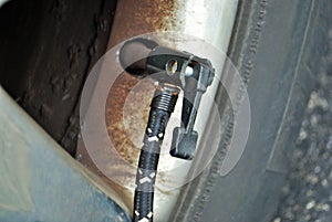 Close up of a portable air compressor connected to the valve stem of a car tire