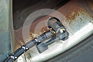 Close up of a portable air compressor connected to the valve stem of a car tire
