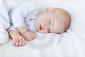 Close-up portrait of adorable baby boy sleeping in bed