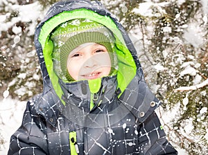 Close up portrait of adorable happy little boy grinning happily at the camera on a sunny winter`s day