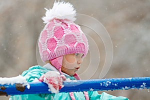 Close-up portrait of adorable little girl wearing knitted pink hat outdoors
