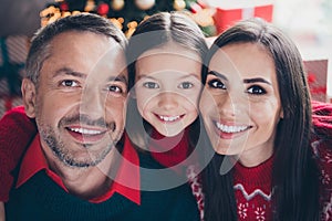 Close up portrait of adorable positive girl cuddle cheerful parents beaming smile newyear magic spirit house inside