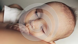 Close-up portrait of adorable sleep baby boy in mother arms.