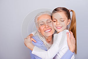 Close up portrait of adorable small lovely sweet charming beautiful girl hugging her careful attentive with white hair granny