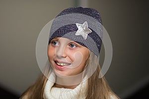 Close-up portrait of adorable smiling child girl wearing knitted hat