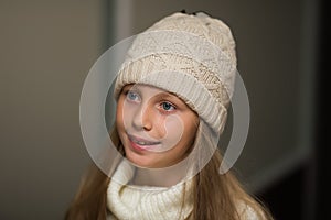 Close-up portrait of adorable smiling child girl wearing knitted hat