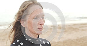 Close-up portrait of an adult young woman with hair flying in the wind against the background of the sea