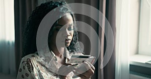 Close up portrait of an African American female with curly hair entering her credit card details on her smartphone while