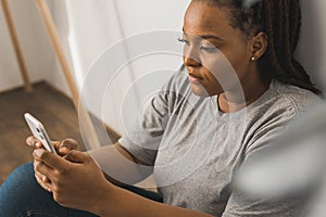 Close-up Portrait of African American female student dressed casually holding mobile phone and typing messages and
