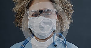 Close-up portrait of African American lady nurse wearing scrubs and face mask with glasses and stethoscope looking at