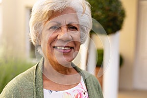 Close-up portrait of african american senior woman smiling while standing outdoors